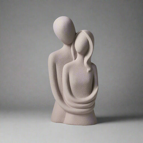 Abstract sculpture of two figures embracing on a gray background