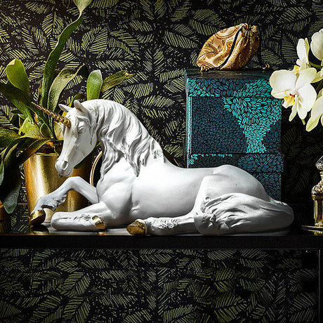 Decorative unicorn figure on a shelf with plants, lamp, and artwork in the background.