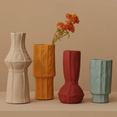 Four ceramic vases in different colors with a beige background